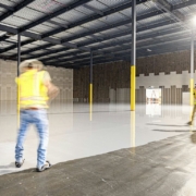 Workers in a large, empty warehouse with polished floors.