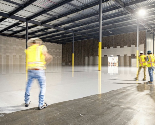 Workers in a large, empty warehouse with polished floors.