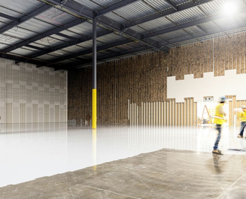 Two construction workers in a large empty warehouse