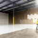 Two construction workers in a large empty warehouse