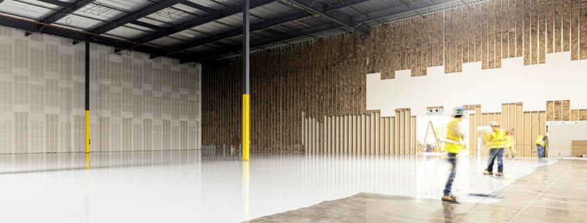 Two construction workers in a large empty warehouse